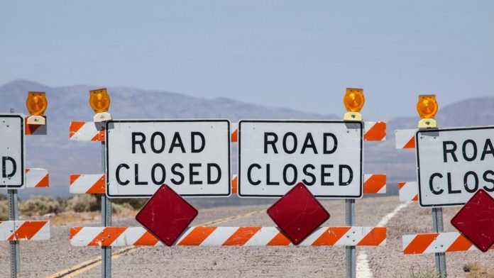 Highway road closure signs and barricades near Route 66 in the California Mojave Desert.